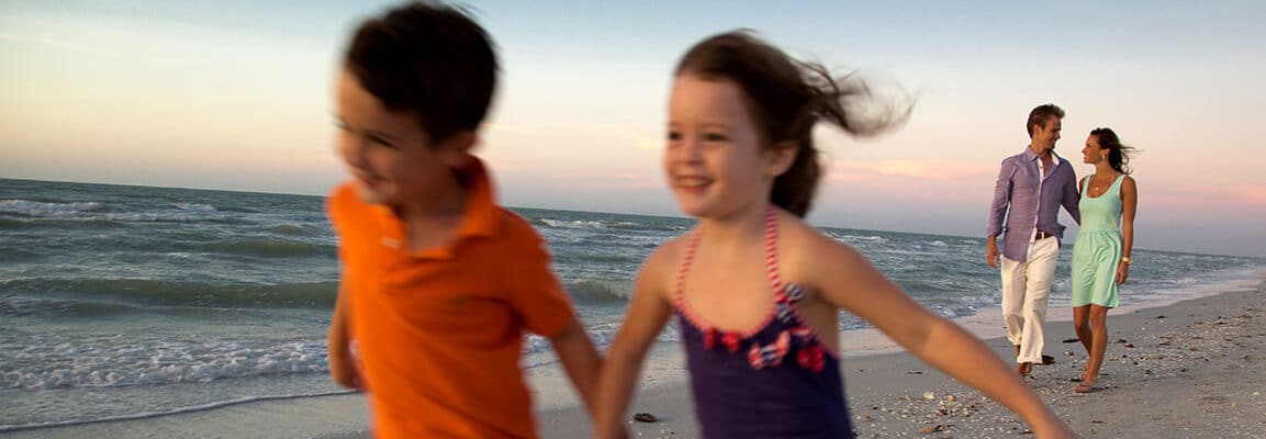 kids run ahead of parents during walk on the beach sanibel island
