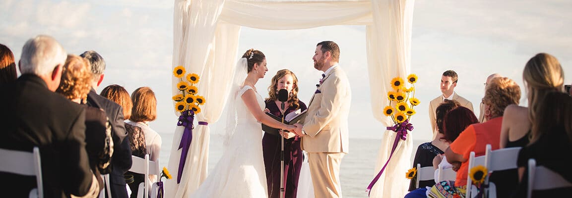 bride and groom at altar with gulf of mexico in background sunflowers