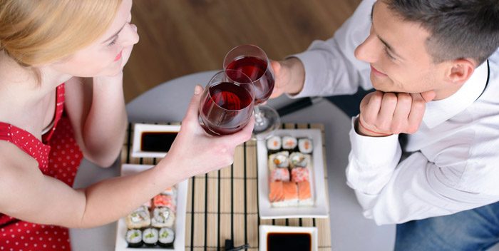 Couple with wine and plates of sushi. 