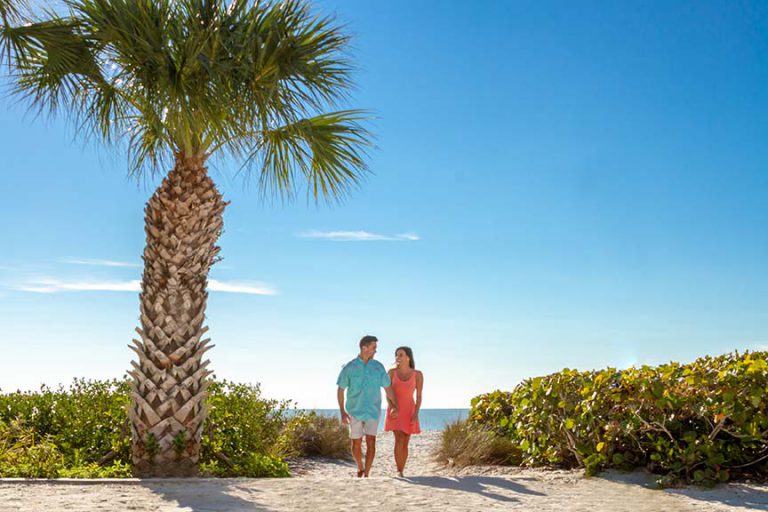 couple walking from beach path sanibel sundial