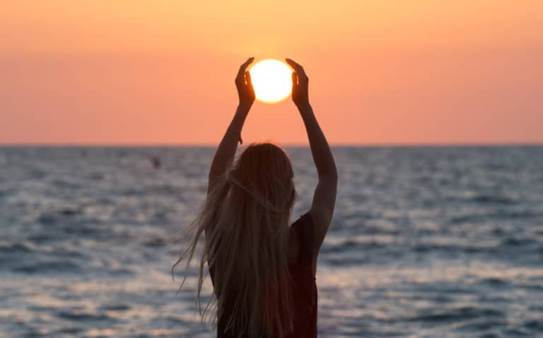 woman holding sun beach sundial sanibel island sunrise sunset