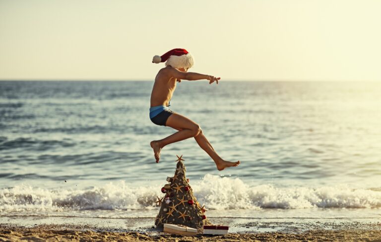 kid in santa hat jumping over christmas tree at beach holiday hotel offer