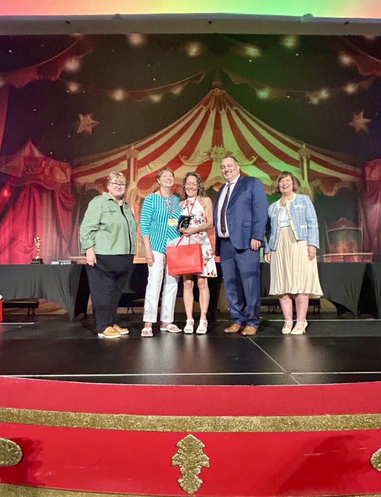 2025 E Awards for Lee County CVB stage antoinette receiving nominee gift bag with CVB reps