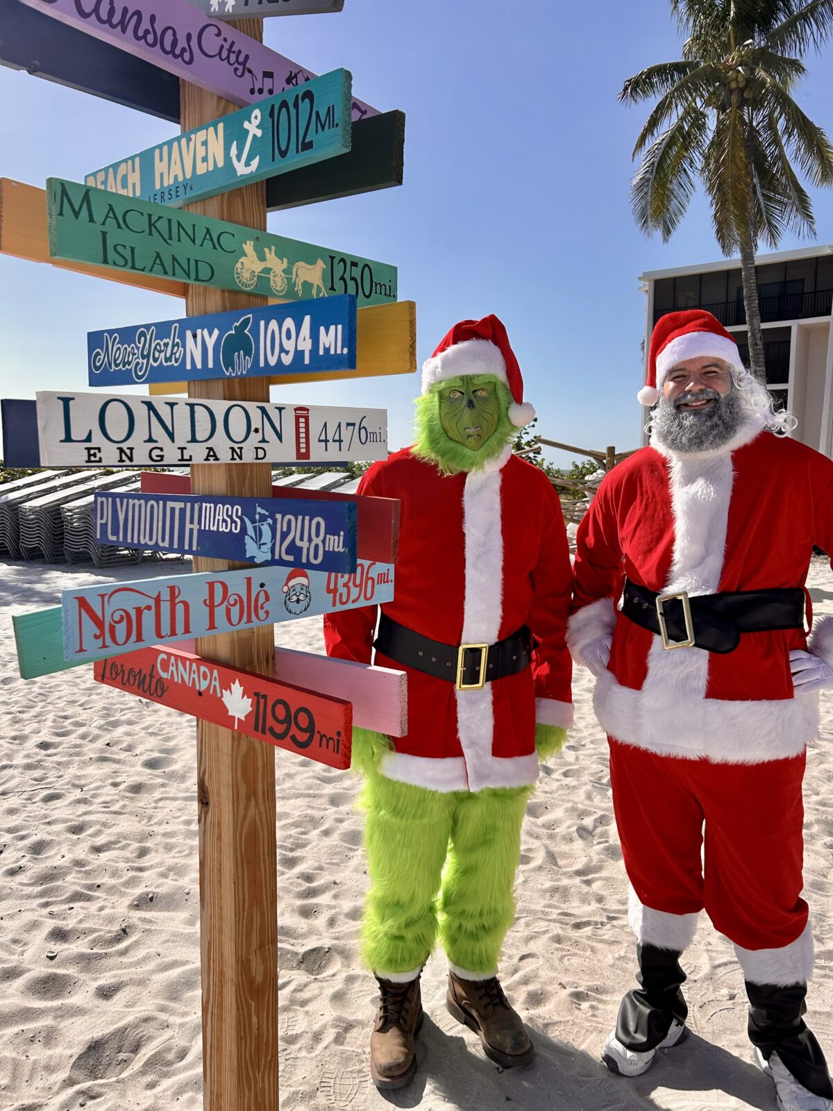 The grinch and santa standing but the sundial resort direction sign on the beach