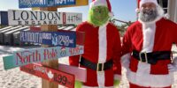 The grinch and santa standing but the sundial resort direction sign on the beach