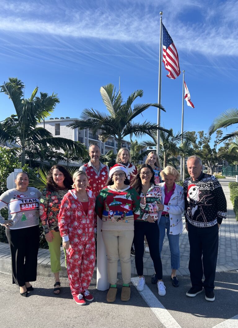 sundial employees showing off their ugly christmas sweaters standing in front of the resort