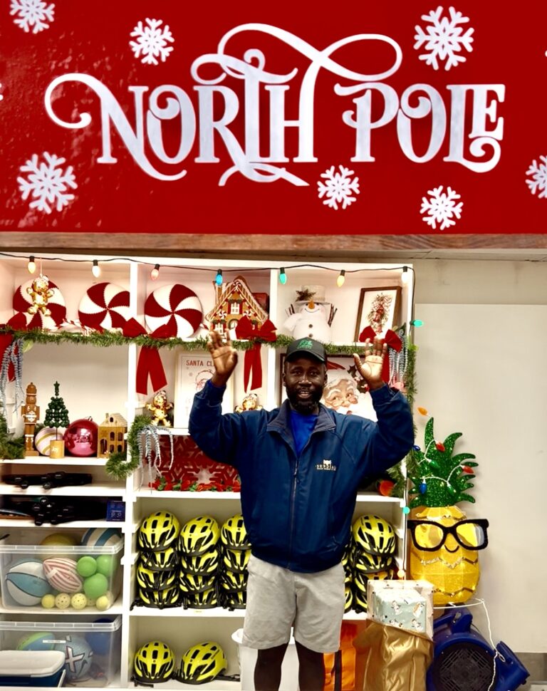 rec shack team member posing under holiday North Pole sign at the rec shack