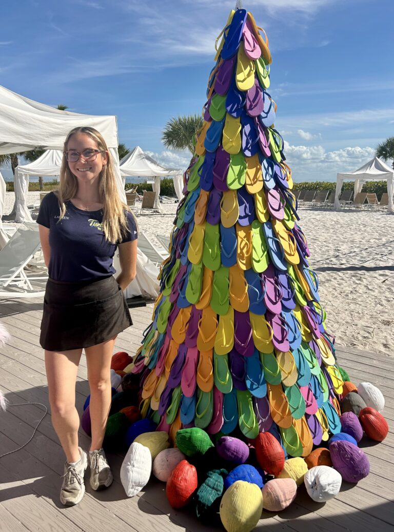 sundial staff member in uniform posing with flip flop tree on the pool deck