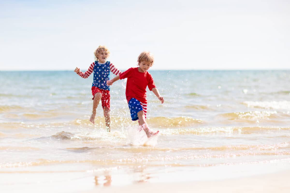 Kids with American flag on beach. 4th of July.