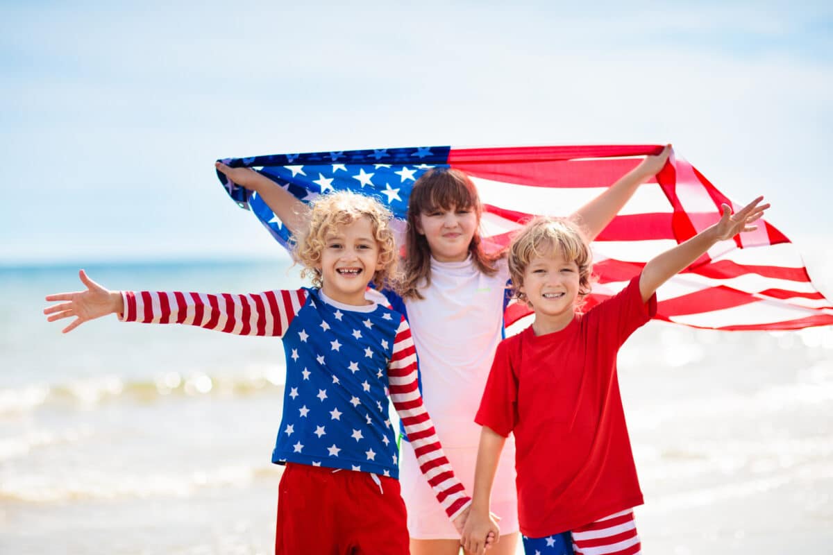 Kids with American flag on beach. 4th of July.