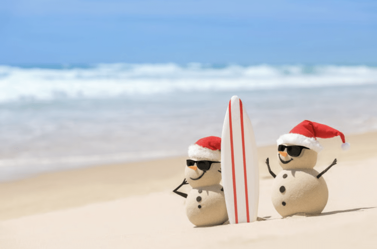 san snowmen with christmas hats and surfboard on beach small