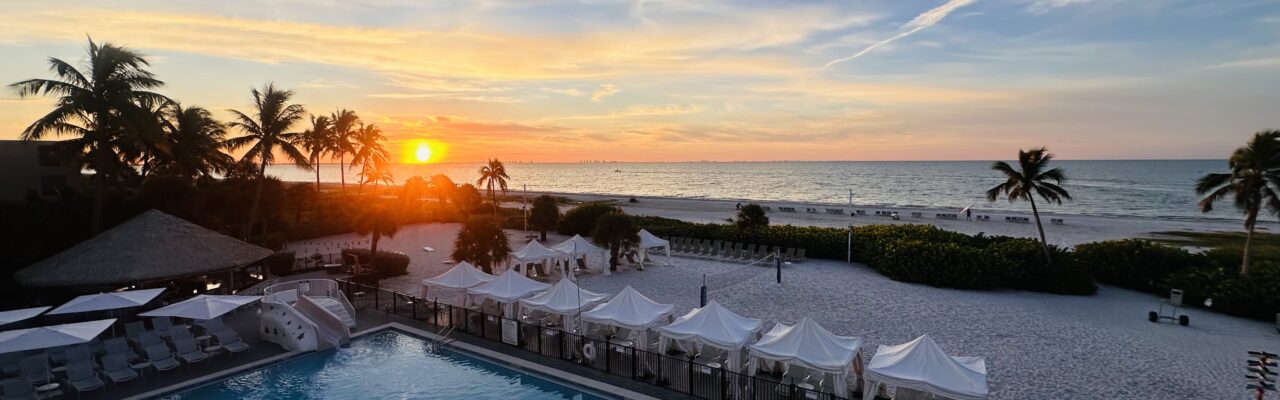 view of bright orange sunrise from Sundial Resort pool and beach