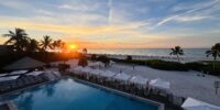 view of bright orange sunrise from Sundial Resort pool and beach